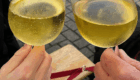 Zwei Personen stoßen mit Gläsern Weißwein beim Weinstand des Frauenchors Lorsbach an.