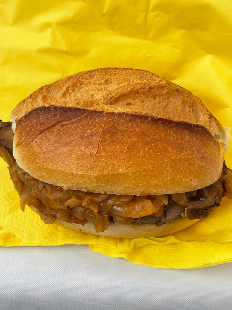 Spießbratenbrötchen mit Schmorzwiebeln auf einer gelben Serviette.